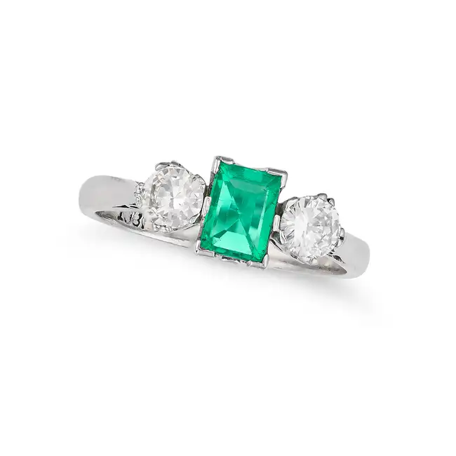 AN EMERALD AND DIAMOND THREE STONE RING set with a rectangular step cut emerald of approximately 0.