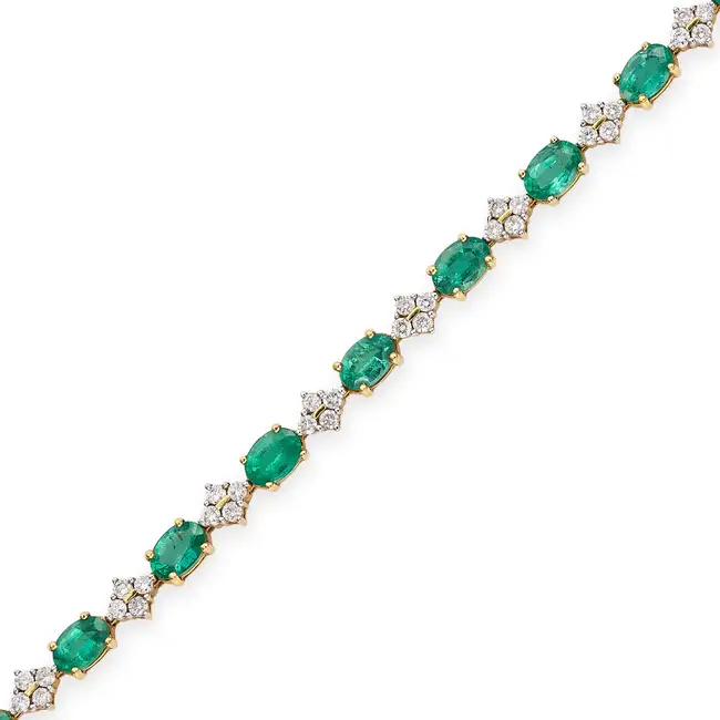AN EMERALD AND DIAMOND BRACELET in 18ct yellow gold, comprising a row of oval cut emeralds, accented
