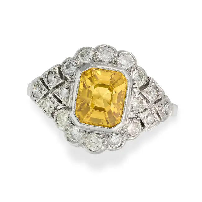 A YELLOW SAPPHIRE AND DIAMOND DRESS RING set with an octagonal step cut yellow sapphire of