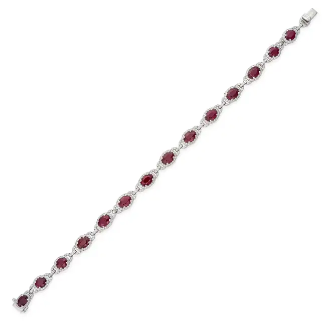 OSCAR FRIEDMAN, A RUBY AND DIAMOND BRACELET set with a row of oval cut rubies in borders of round