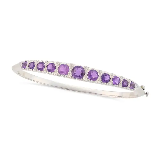 AN AMETHYST AND DIAMOND BANGLE the hinged bangle set with a row of graduating round cut amethysts,