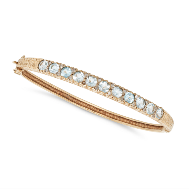 A VINTAGE BLUE TOPAZ AND DIAMOND BANGLE in yellow gold, the hinged bangle set with a row of round cut blue topaz accented by round cut diamonds, no assay marks, inner circumference 17.9cm, 12.6g. 