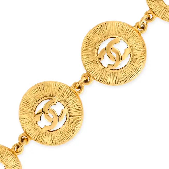 CHANEL, A SUNBURST BRACELET comprising four textured circular gold tone metal links with an
