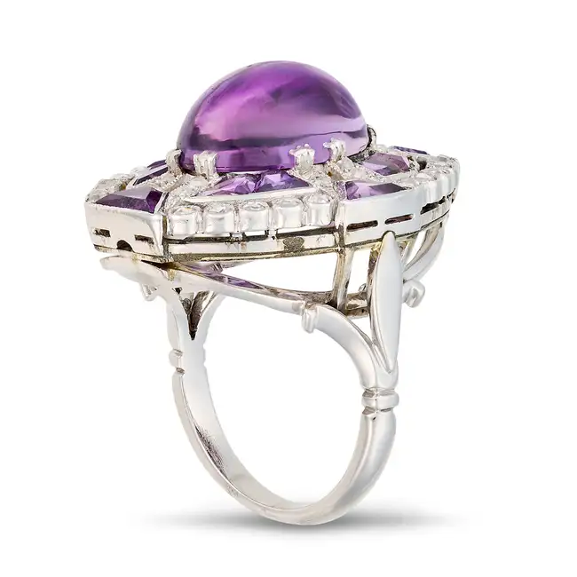 A VINTAGE AMETHYST AND DIAMOND DRESS RING set with an oval cabochon amethyst, accented by calibre