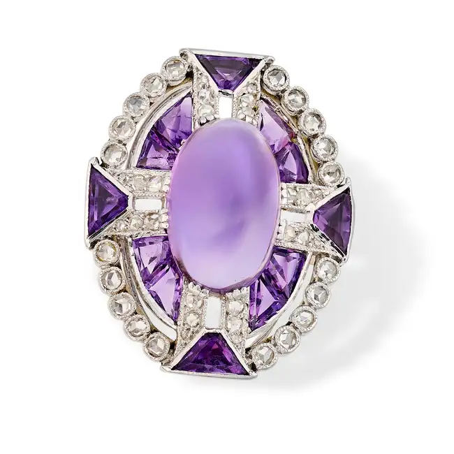 A VINTAGE AMETHYST AND DIAMOND DRESS RING set with an oval cabochon amethyst, accented by calibre