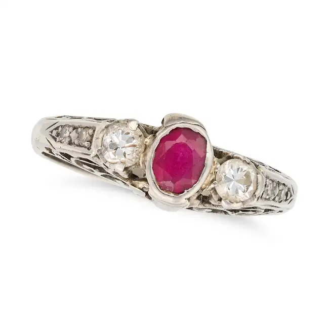 NO RESERVE - A RUBY AND DIAMOND THREE STONE RING set with an oval cut ruby between two round cut