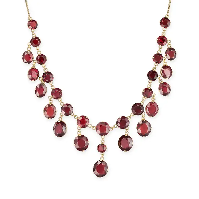 A GARNET FRINGE NECKLACE comprising a trace chain set with a row of round cut garnets, suspending