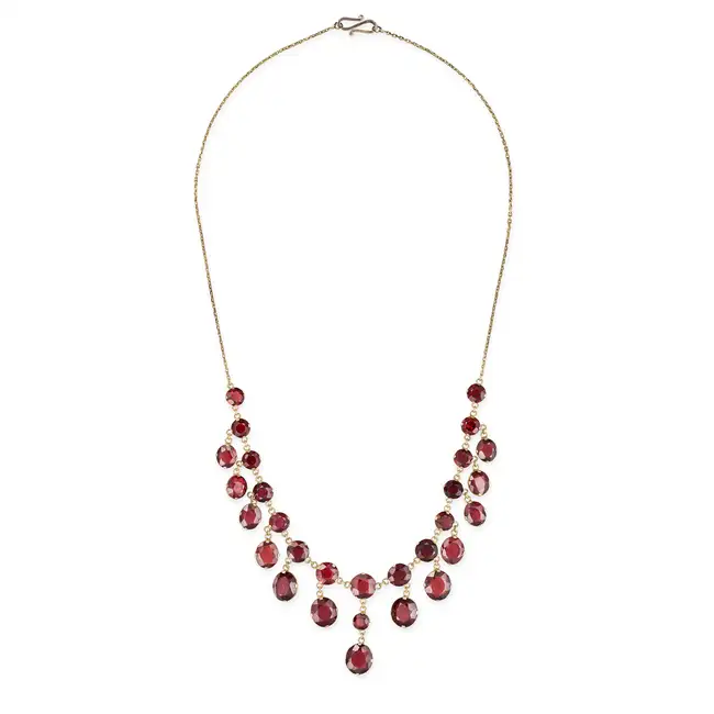 A GARNET FRINGE NECKLACE comprising a trace chain set with a row of round cut garnets, suspending