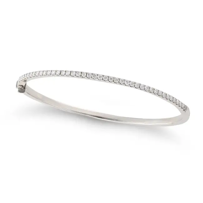 A DIAMOND BANGLE in platinum, the hinged bangle set to one half with a row of round brilliant cut