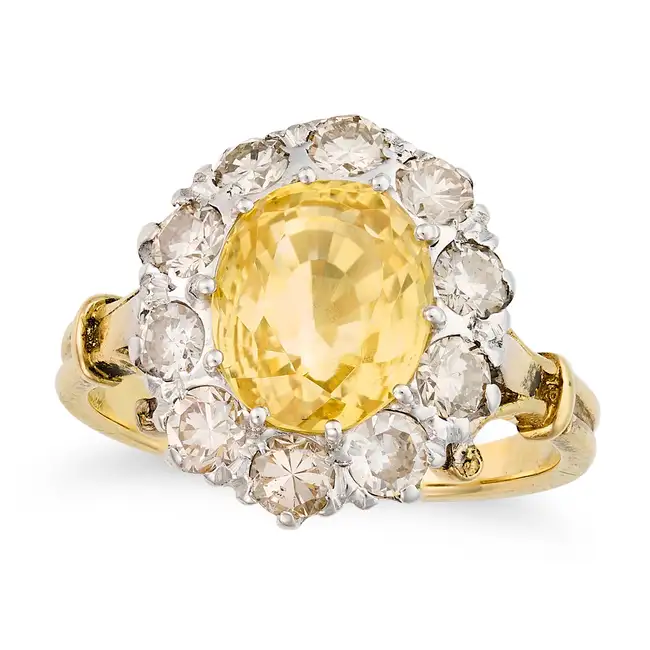 A FINE YELLOW SAPPHIRE AND DIAMOND CLUSTER RING set with an oval cut yellow sapphire of