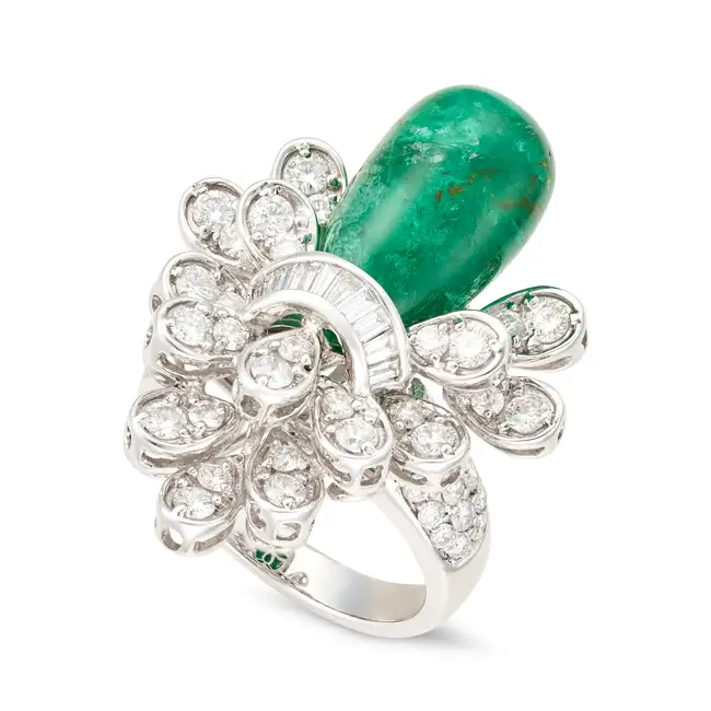 AN EMERALD AND DIAMOND COCKTAIL RING set with a polished emerald drop within a tiered spray of round