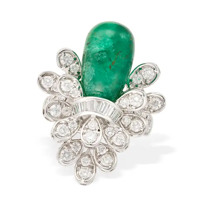 AN EMERALD AND DIAMOND COCKTAIL RING set with a polished emerald drop within a tiered spray of round