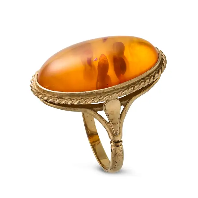 NO RESERVE - A VINTAGE AMBER RING in 9ct yellow gold, set with an oval cabochon amber within a