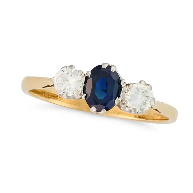 NO RESERVE - A SAPPHIRE AND DIAMOND THREE STONE RING in yellow gold, set with an oval cut sapphire