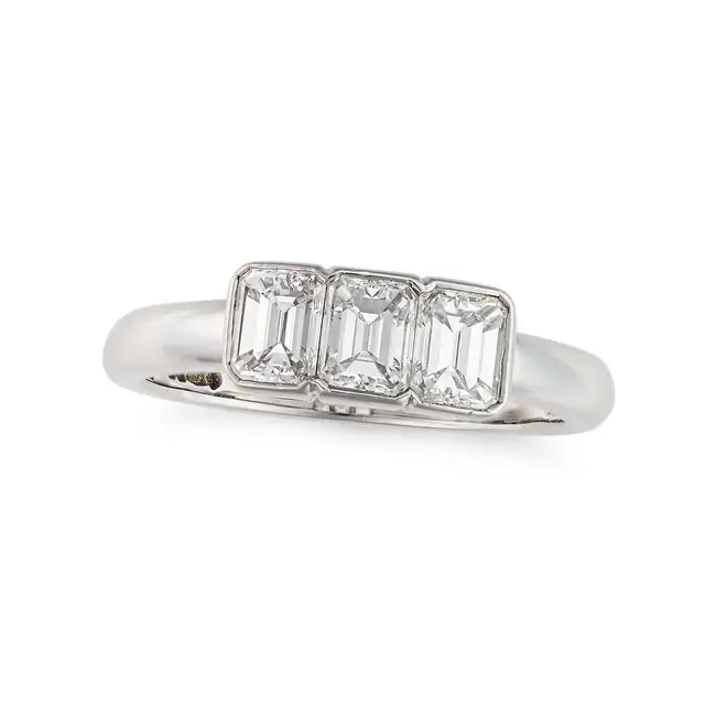 A THREE STONE DIAMOND RING in platinum, set with three emerald cut diamonds totalling 1.1-1.2