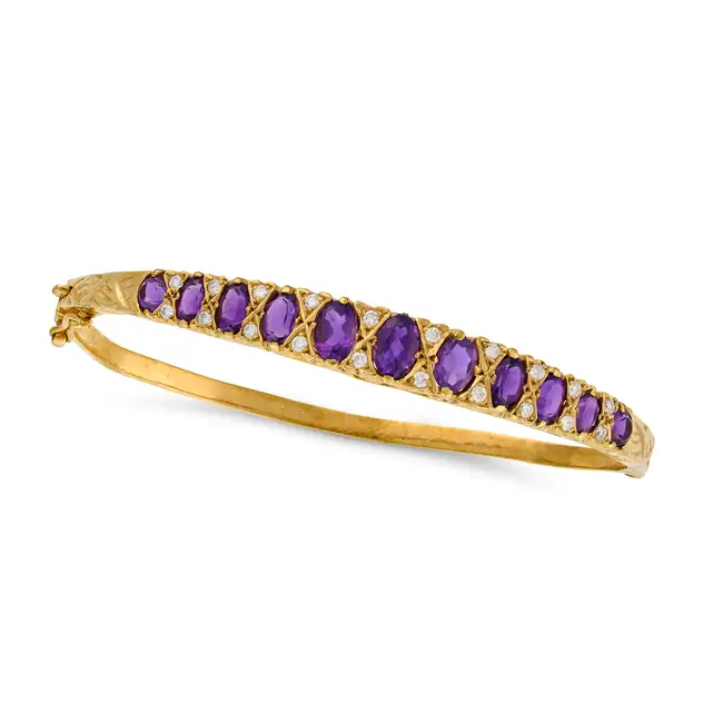 AN AMETHYST AND DIAMOND BANGLE the hinged bangle set with a row of graduating oval cut amethysts,