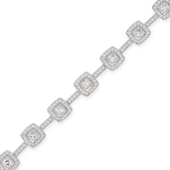 A DIAMOND BRACELET comprising a row of links set with cushion cut diamonds in borders of round