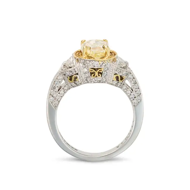 A FANCY LIGHT YELLOW DIAMOND AND DIAMOND RING in platinum, set with an oval cut yellow diamond of