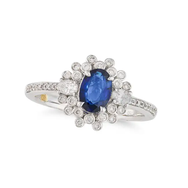 A SAPPHIRE AND DIAMOND CLUSTER RING in 18ct white gold, set with an oval cut sapphire of