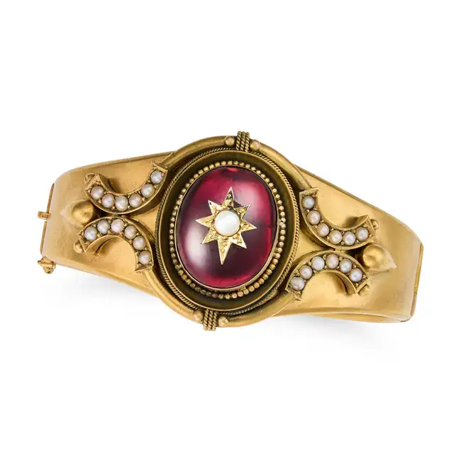 AN ANTIQUE VICTORIAN GARNET AND PEARL BANGLE  the hinged bangle comprising an oval cabochon garnet
