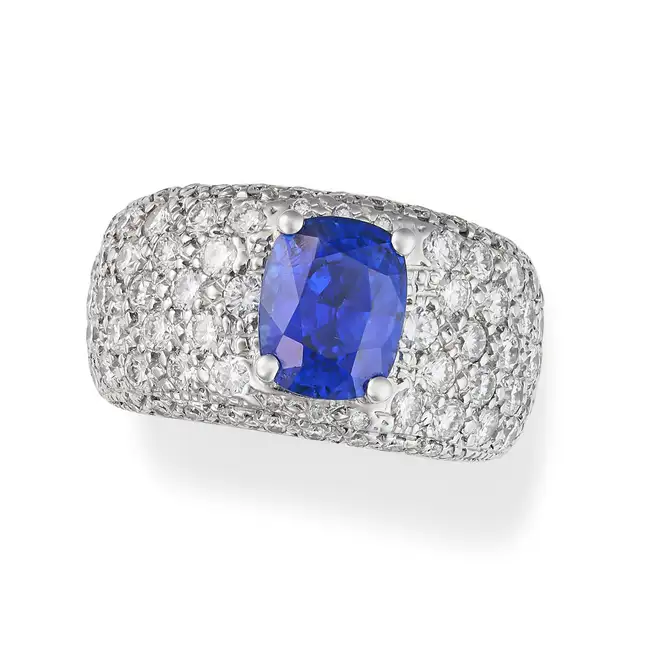 A SAPPHIRE AND DIAMOND BOMBE RING in platinum, set with a cushion cut sapphire of approximately 2.95