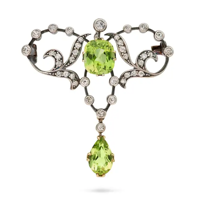 AN ANTIQUE PERIDOT AND DIAMOND BROOCH in yellow gold and silver, the scrolling brooch set with a