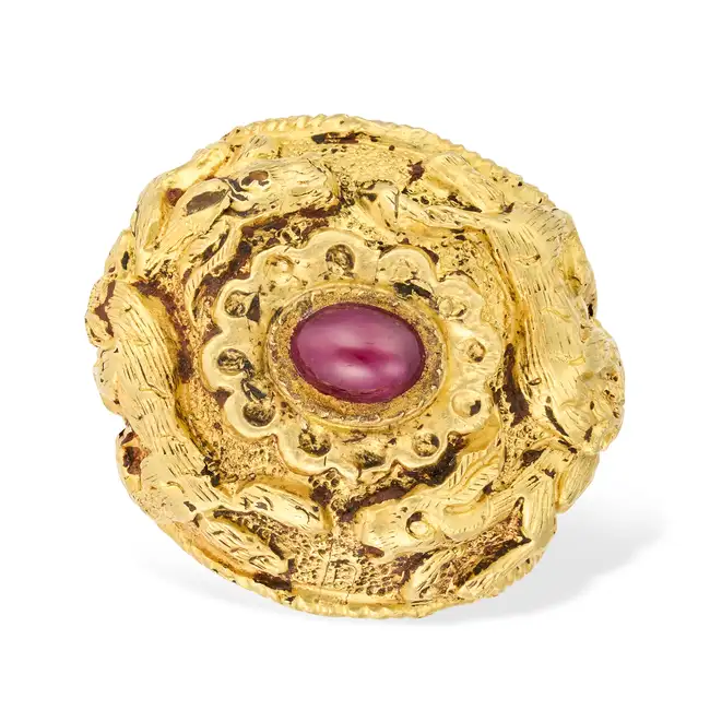 A RUBY DRESS RING the highly ornate band featuring animals in high relief figures and scrollwork,
