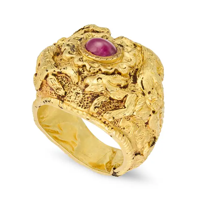 A RUBY DRESS RING the highly ornate band featuring animals in high relief figures and scrollwork,