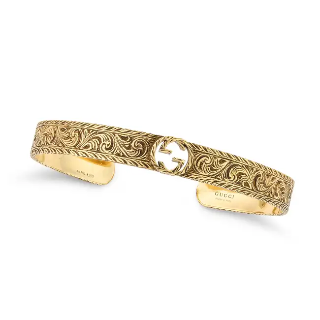 GUCCI, A GOLD CUFF BANGLE in1 8ct yellow gold, the open cuff bangle with the Gucci logo, engraved