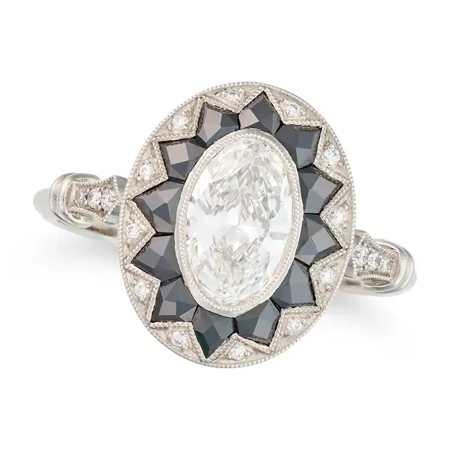 A FINE DIAMOND AND ONYX DRESS RING in platinum, set with an oval cut diamond of 0.77 carats,
