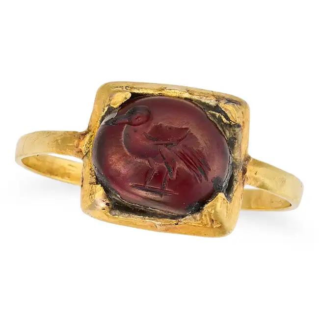 AN ANTIQUE GARNET INTAGLIO RING in yellow gold, set with a cabochon garnet carved to depict a