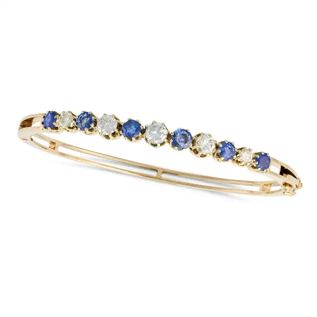 A SAPPHIRE AND DIAMOND BANGLE the hinged bangle set with a row of alternating round cut sapphires