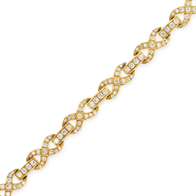 A DIAMOND BRACELET comprising a row of round brilliant cut diamonds, accented by stylised X motifs