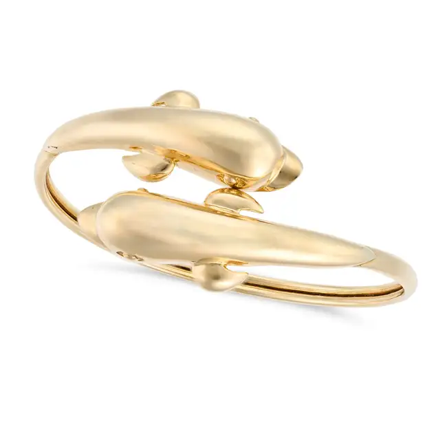 A GOLD DOLPHIN BANGLE in crossover design, terminating at each end with a dolphin motif, stamped