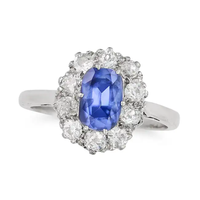 A SAPPHIRE AND DIAMOND CLUSTER RING in 18ct white gold, set with a cushion cut sapphire of