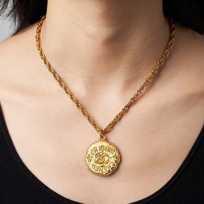 CHANEL, A CC MEDALLION PENDANT NECKLACE comprising a fancy link chain with a circular medallion