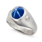 A SYNTHETIC STAR SAPPHIRE AND DIAMOND RING set with a cabochon star sapphire of approximately 3.10