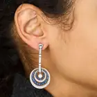 A PAIR OF DIAMOND AND SAPPHIRE DROP EARRINGS each suspending a round brilliant cut diamond within