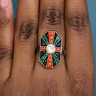 AN ART DECO DIAMOND, CORAL, ONYX AND EMERALD DRESS RING set with a round brilliant cut diamond of