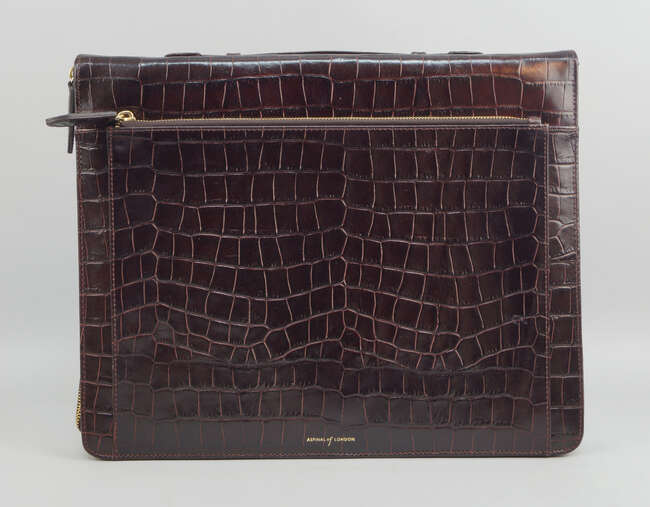 An Aspinal of London brown leather crocodile effect briefcase, with zip closure, suede and...