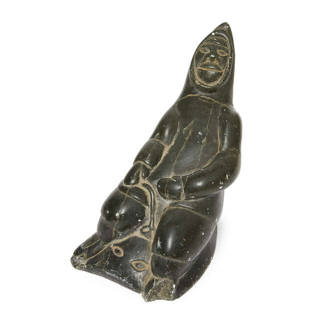 
	
		An Inuit grey soapstone sculpture of a male hunter, late 20th century, carved wearing a...