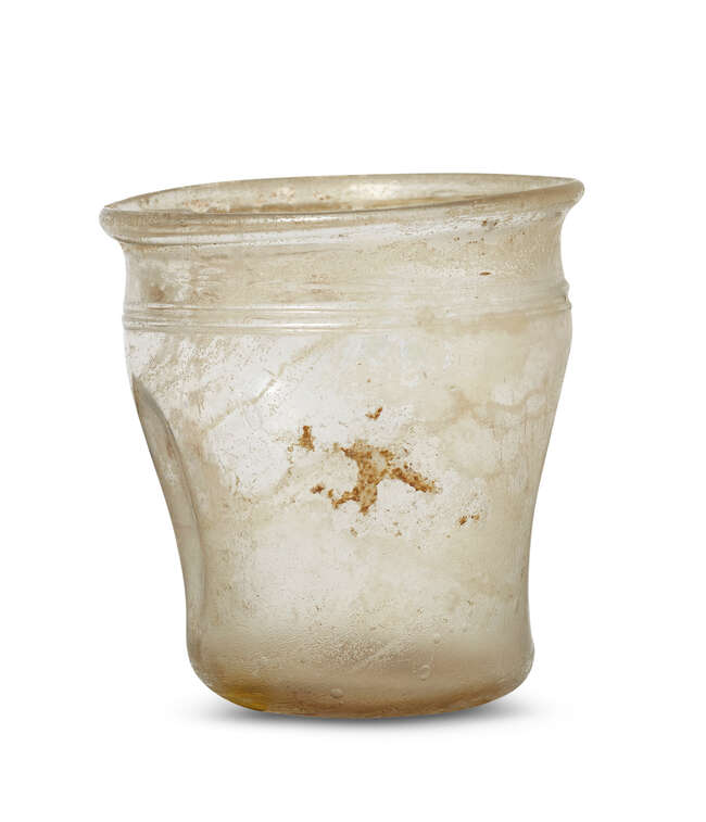 
	
		A Roman glass cup, 2nd-4th century AD, with compressed sides, on a perspex plinth, cup...