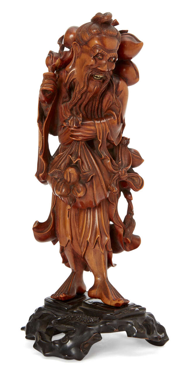 
	
		A Chinese wood carving of an Immortal, 19th century, carved holding a sack of peaches in...