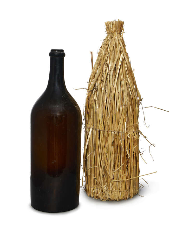 
	
		A French brown glass Jeroboam Champagne bottle, late 19th century, with a straw carriage...