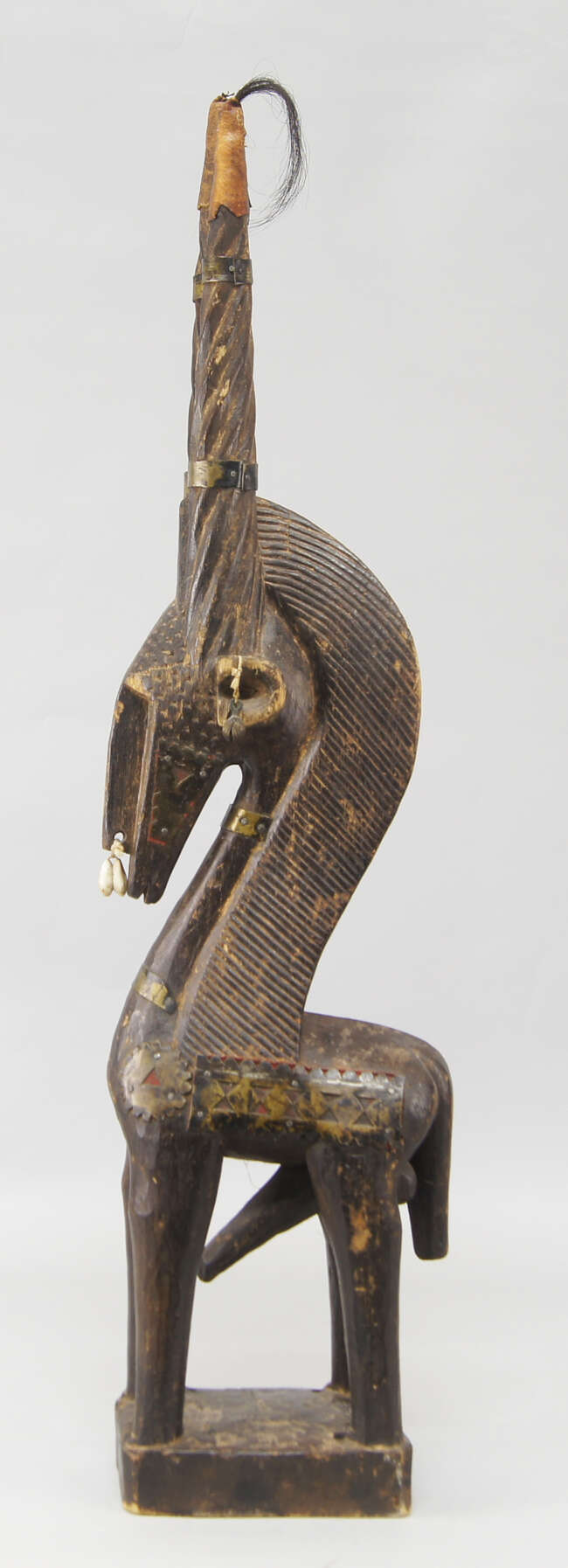 
	
		A tribal antelope sculpture, Bambara, with writhen carved horns, the ears and nose hung...