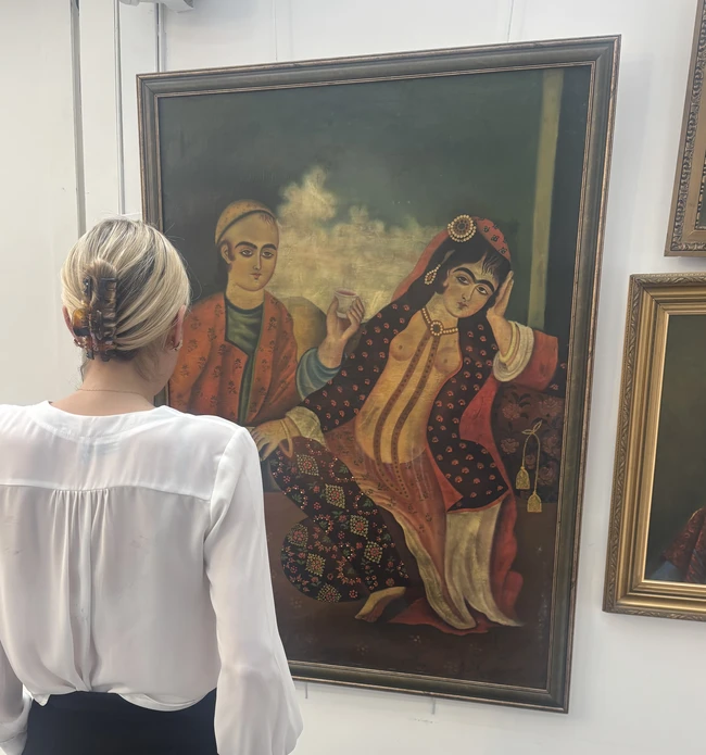 A courtesan and a suitor, Qajar Iran or later, 
Oil on canvas, she reclining on a bolster,...