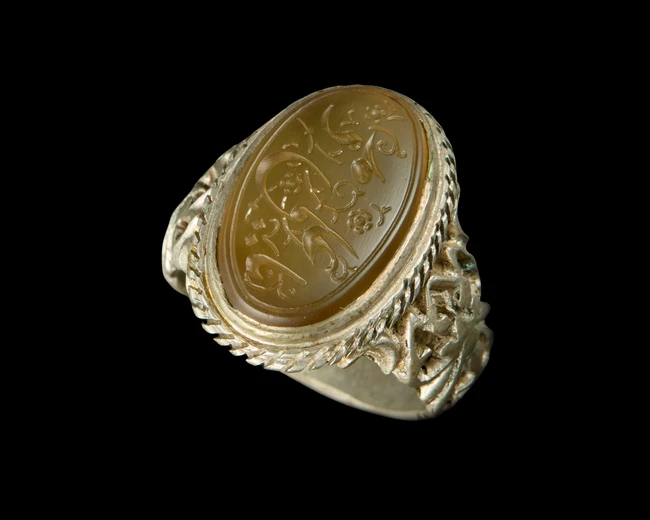 A Qajar ring set with an engraved carnelian seal,Iran, 19th century 
In floral silver mount, the...