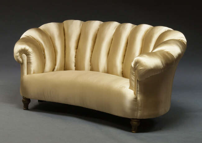
	
		An Art Deco style sofa, with curved frame, the backrest with scalloped design,...