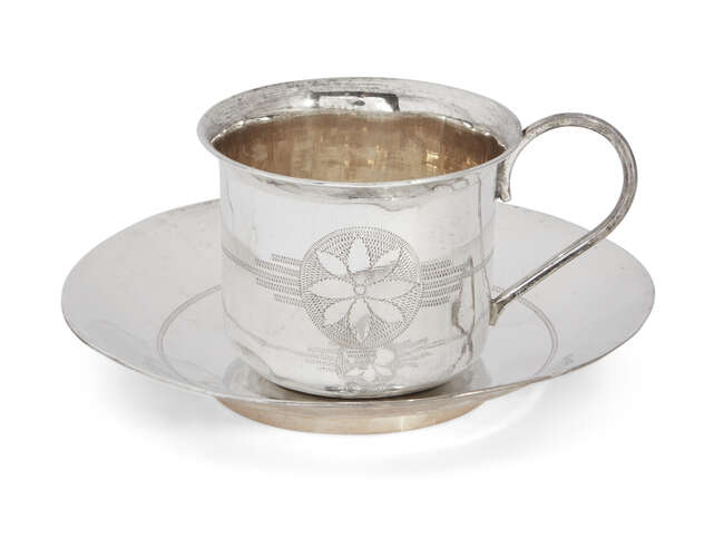 
	
		A bright-cut engraved cup and saucer, unmarked white metal, both decorated with flower...