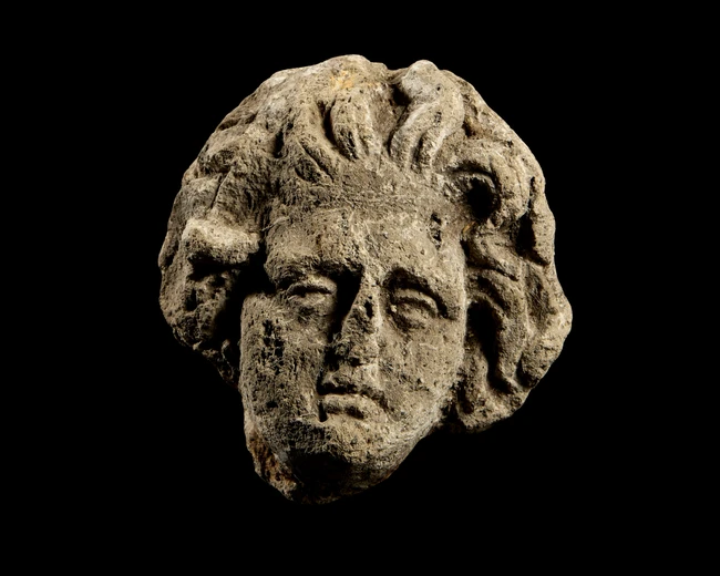 A carved head of a youth, Possibly Roman 4th century,Of porous volvanic stone, hairstyle with...